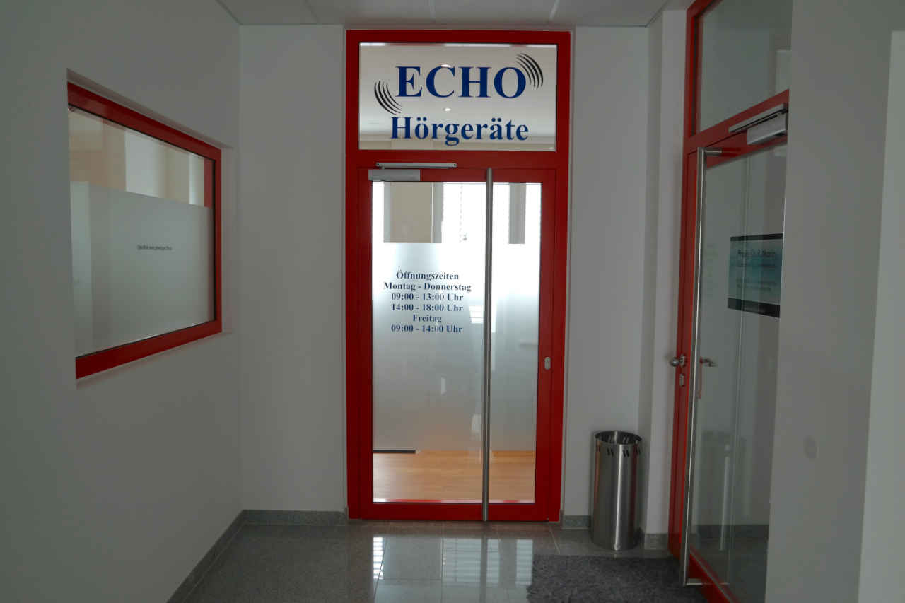 Gläserne Eingangstür mit rotem Metallrahmen